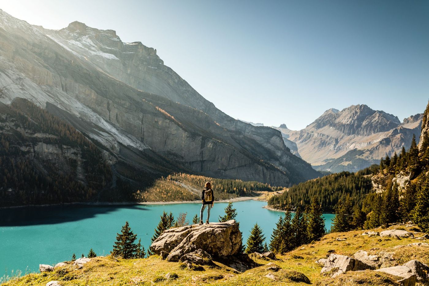 A lone hiker on the forested shore of Lake Oeschinen near the Swiss Alps