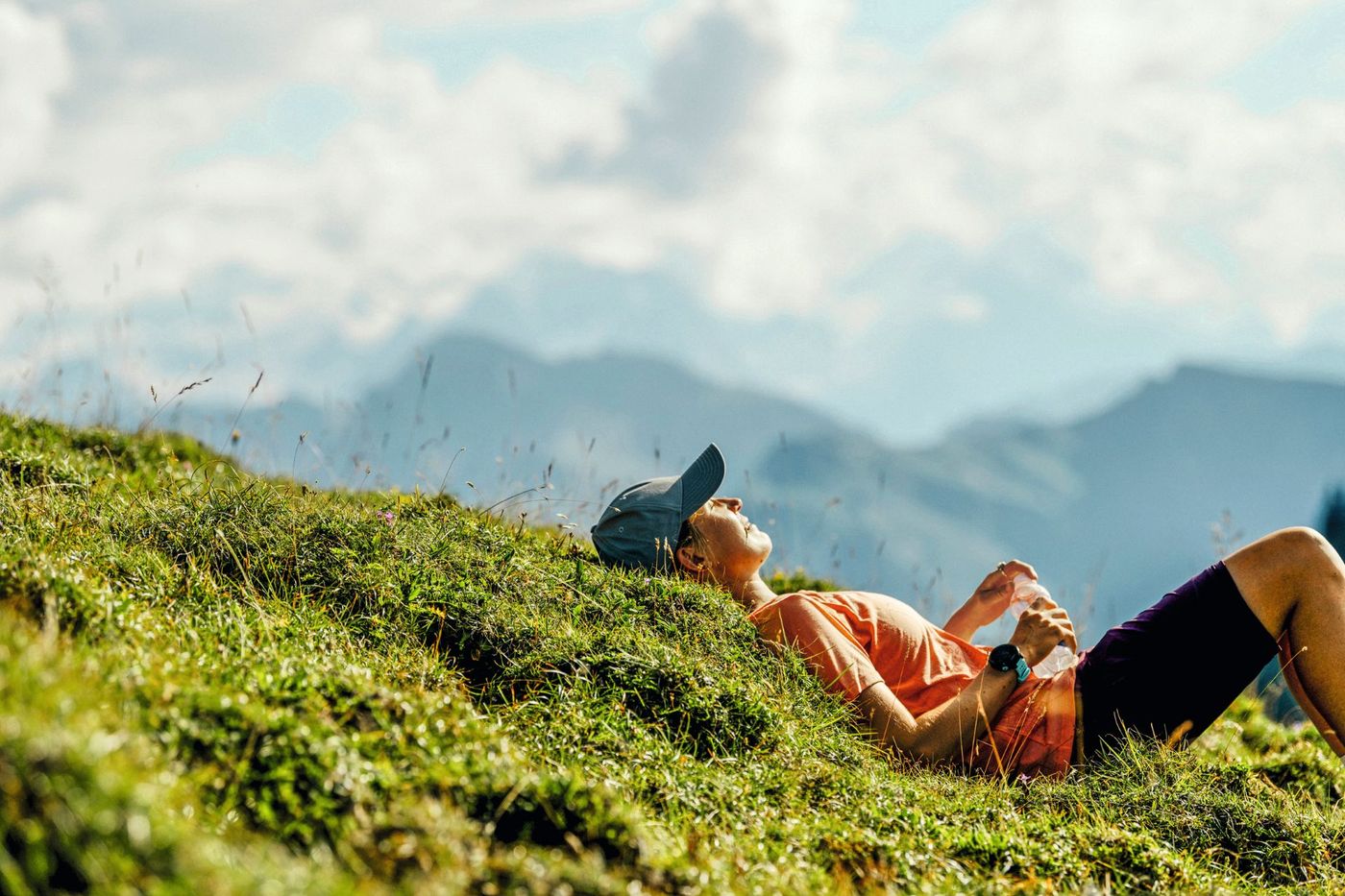 Hiker lying back on a grassy hillside near the Gräfimattnollen peak along the Tell Trail-supplied by Eurotrek