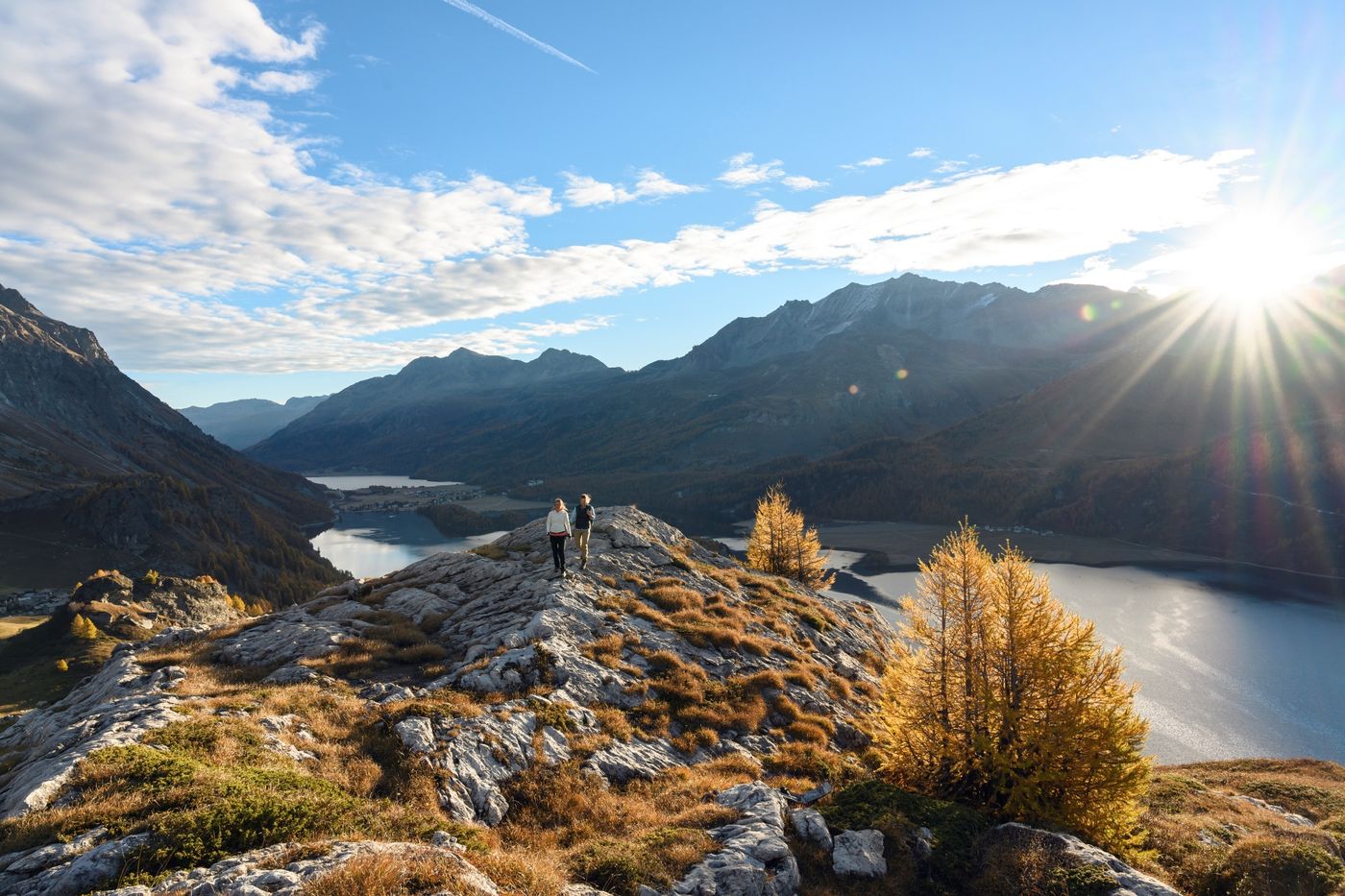 Hikers standing on a rugged, rocky ridge overlooking Lake Sils and Lake Silvaplana-supplied by Eurotrek