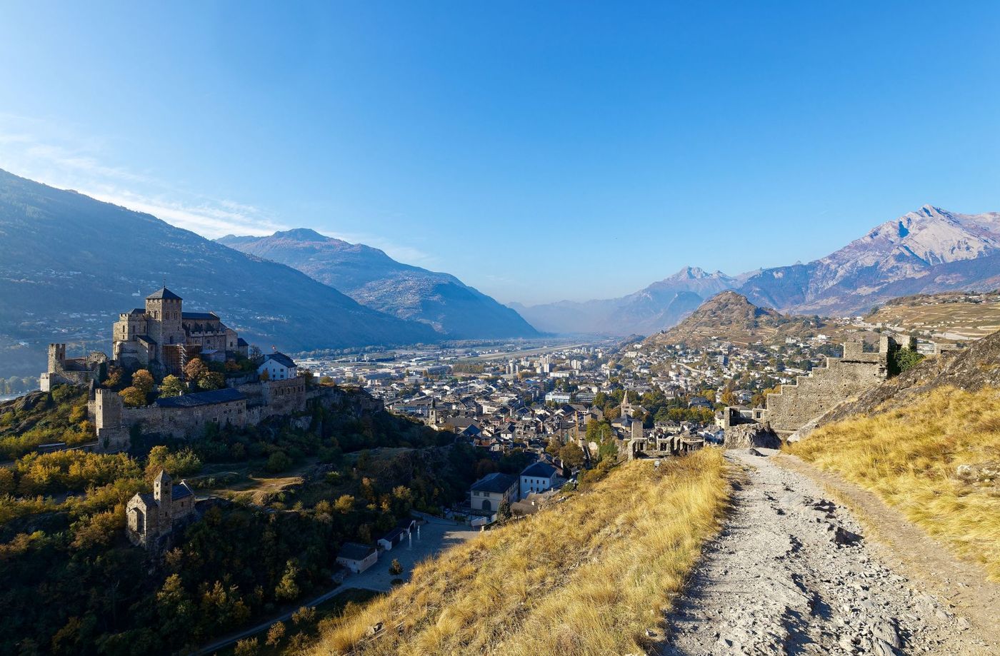 Sunny hillside path looking toward the fortified Valère Basilica in Rhone Valley of Switzerland.