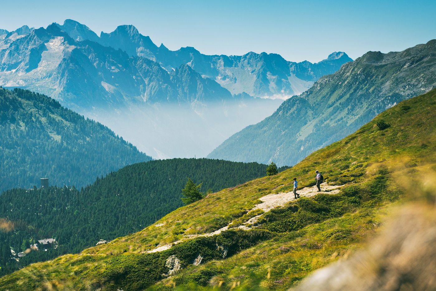 Two hikers traversing a grassy mountain trail on the Via Engiadina near Sils, Switzerland-supplied by Eurotrek